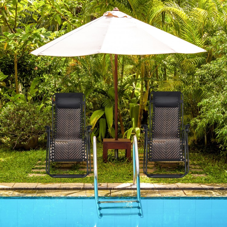 Two folding patio rattan zero gravity lounge chairs under a large umbrella, ideal for poolside relaxation in the garden.