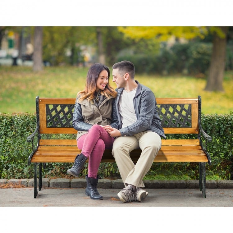 Outdoor cast iron patio bench with solid wood seat, comfortably seating three adults, ideal for garden relaxation.