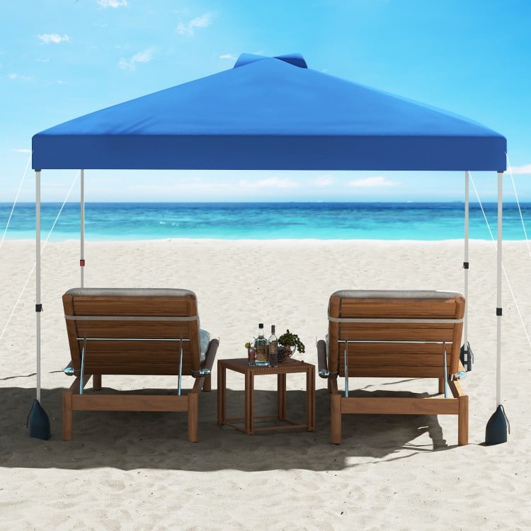 Blue 10 x 10 ft pop-up canopy tent with sidewall, set up on the beach with two lounge chairs for sun protection.
