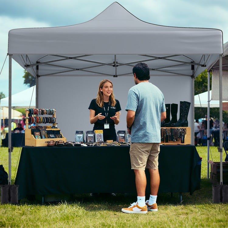 Pop-up canopy tent with gray fabric, removable sidewalls, and a wheeled bag, ideal for outdoor events and markets.