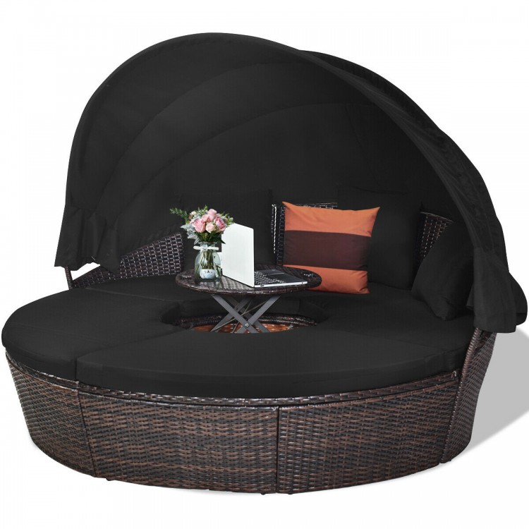 Round outdoor daybed with retractable canopy, black cushions, and adjustable table, perfect for patio or poolside.