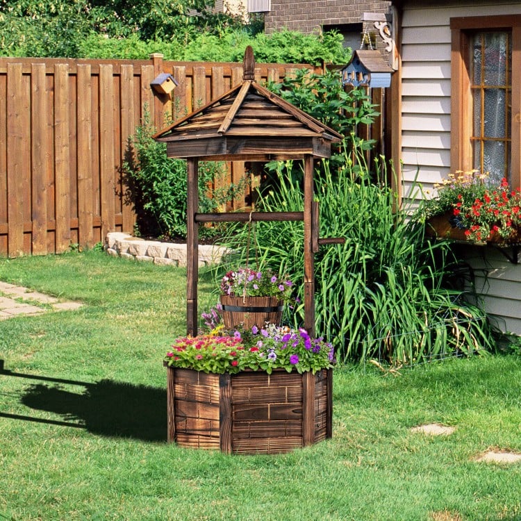 Rustic wooden wishing well planter with adjustable bucket, made of carbonized fir wood, ideal for garden or patio use.