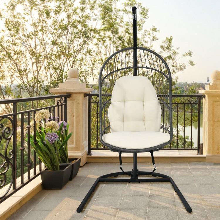 Hanging wicker egg chair with beige cushions and sturdy steel frame, perfect for outdoor patio relaxation.