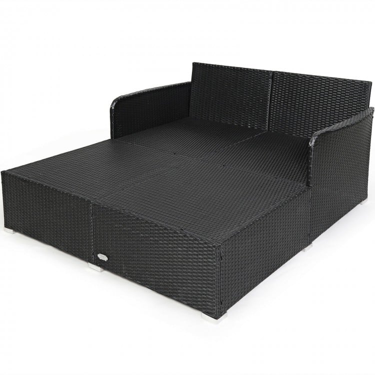 Spacious outdoor rattan daybed in black with upholstered cushions and pillows, perfect for relaxation and comfort.