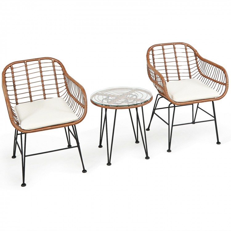 Two rattan armchairs with white cushions and a glass-top side table, perfect for patio or garden relaxation.