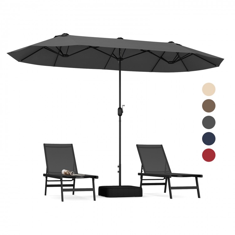 Double-sided gray patio umbrella with crank handle and two lounge chairs, ideal for poolside or garden shade.