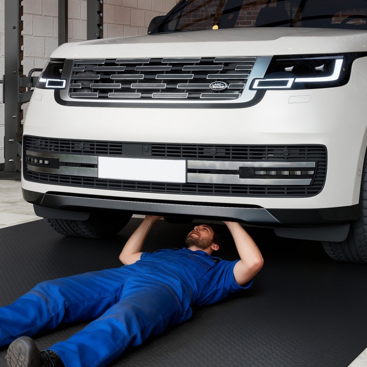 Mechanic working under a vehicle on 7 mm thickened PE garage tool mats, ideal for tool rooms and garages.