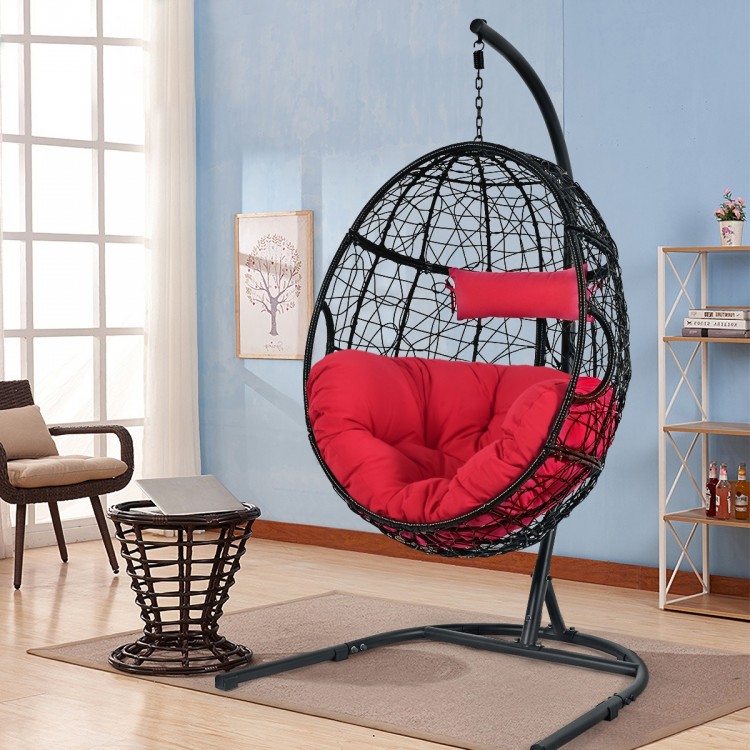 Hanging cushioned hammock chair with stand in red, featuring a rugged frame and comfortable pillow for indoor or.