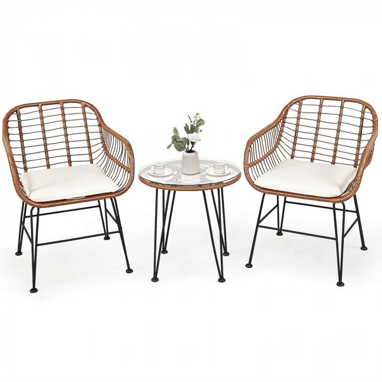 Two armchairs and a side table from the 3 Pieces Patio Rattan Bistro Set with white cushions for outdoor relaxation.