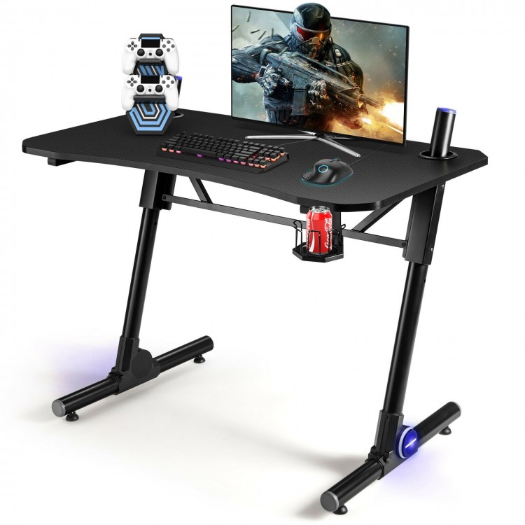 Height adjustable gaming desk with blue LED lights, carbon fiber surface, and sturdy Z-shaped legs for stability.