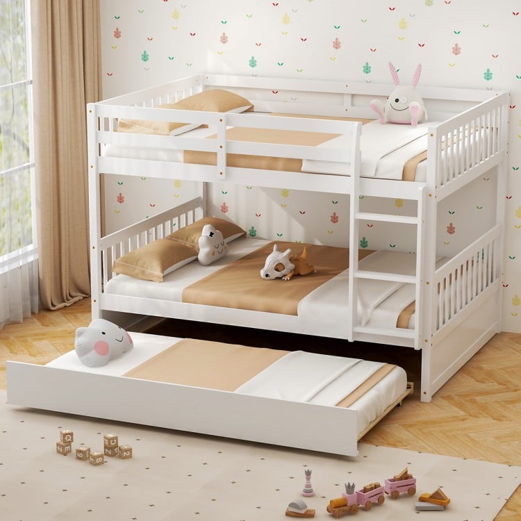 Trundle bed pulled out from under the full over full bunk bed in white wood, offering extra sleeping space for guests.