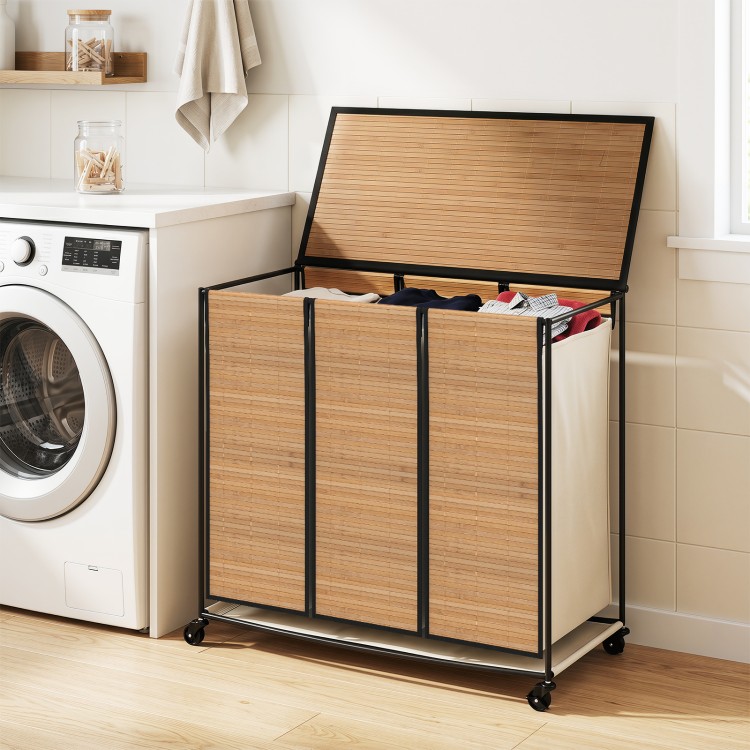 Three-section laundry hamper with lid and natural bamboo slats, designed for sorting clothes in small spaces.