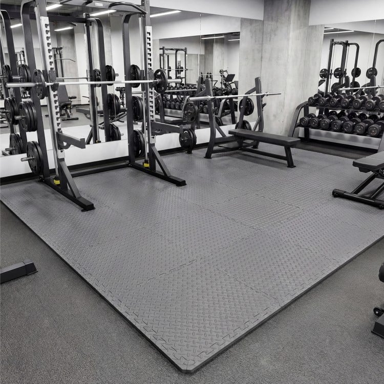 Gray 1/2" puzzle exercise floor mats in a gym setting, providing a non-slip, cushioned surface for workouts.
