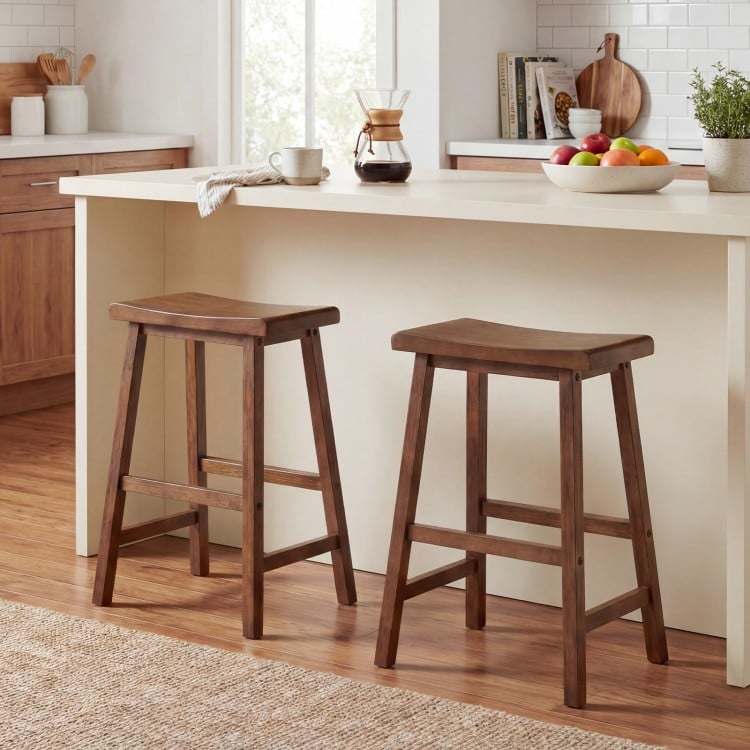 Set of 2 brown 24-inch counter height stools with solid wood saddle seats, ideal for kitchen island seating.