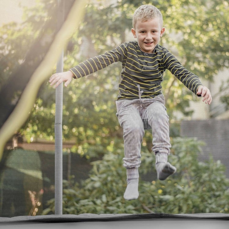 Child jumping on a trampoline with a weather-resistant safety enclosure net for secure and enjoyable play.