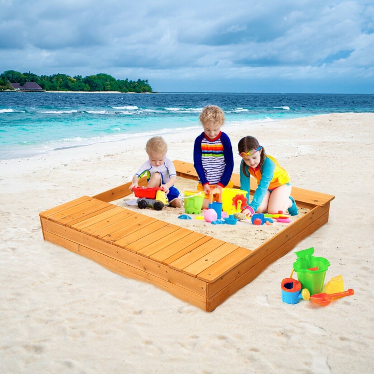 Kids playing in a cedar sandbox on the beach, featuring storage boxes and spacious design for creativity and fun.
