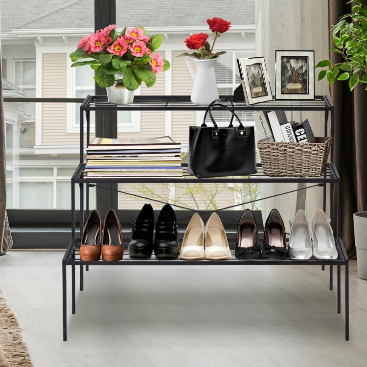 Three-tier metal plant stand in black, showcasing shoes and decorative items, ideal for indoor or patio use.