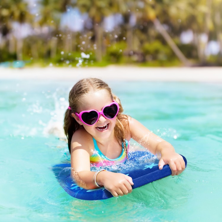 Child with pink heart-shaped sunglasses enjoying a 41-inch lightweight bodyboard in clear water, perfect for summer fun.