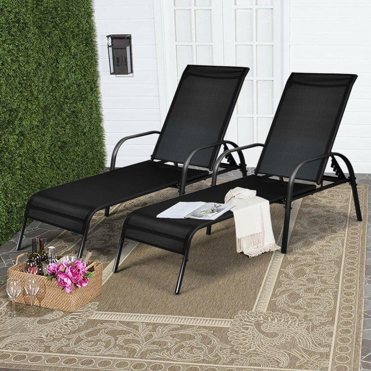 Two adjustable outdoor patio lounge chairs with black fabric and sturdy steel frames, perfect for poolside relaxation.