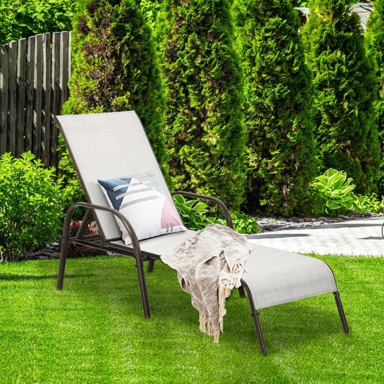 Gray outdoor patio lounge chair with adjustable reclining armrest, set in a lush garden for relaxation and comfort.