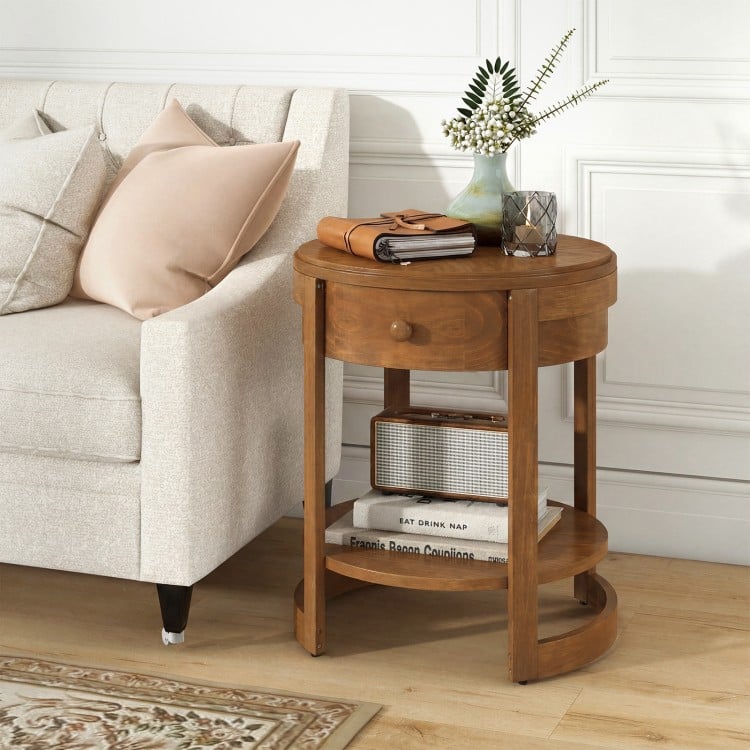 Round end table with oak finish, featuring a drawer and lower shelf, perfect for displaying decorative items.