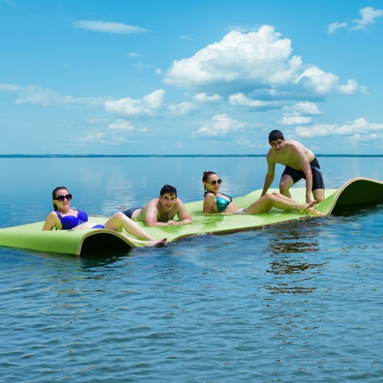 Floating water pad in green, 12’ x 6’, with four people enjoying relaxation on a lake under a sunny sky.