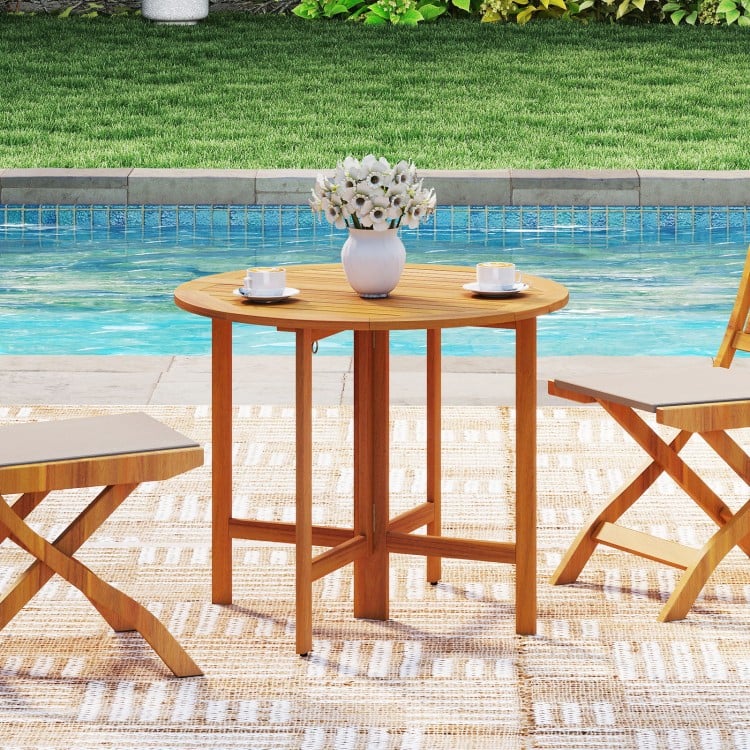 Round 36-inch outdoor folding dining table made of acacia wood, perfect for backyard gatherings by the pool.
