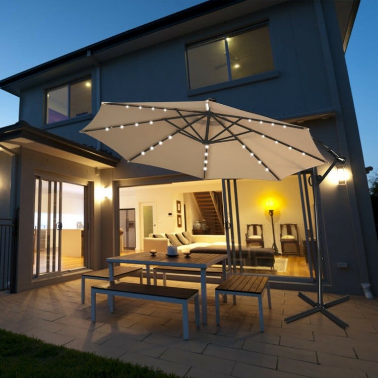 Beige 10 ft solar-powered LED patio offset umbrella with 360° rotation, perfect for outdoor dining and relaxation.