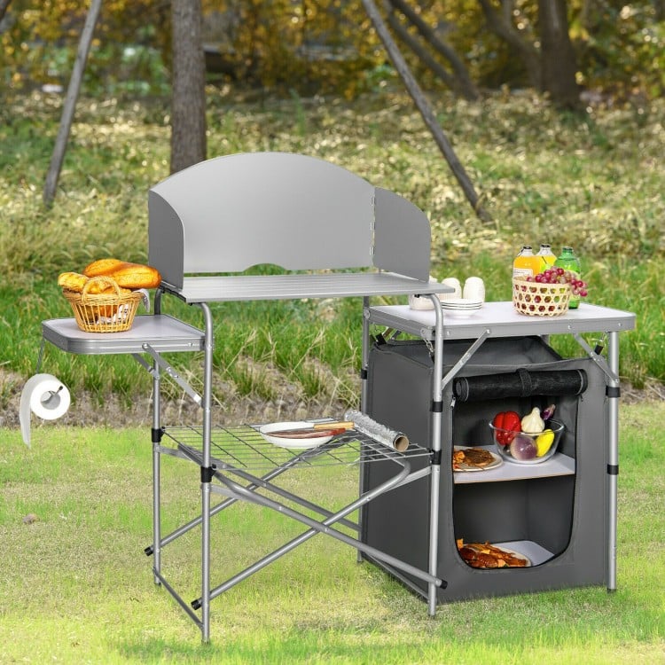 Foldable outdoor BBQ grilling table in gray with windscreen, side tables, and storage bag, ideal for camping and.