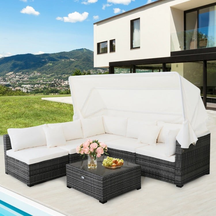 6-piece patio rattan furniture set with retractable canopy, featuring white cushions and a glass tabletop for outdoor.