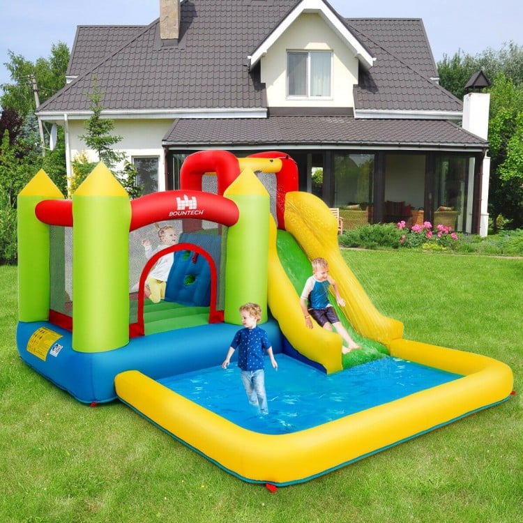 Inflatable bounce house water slide with climbing wall and splash pool for outdoor fun and exercise for kids.