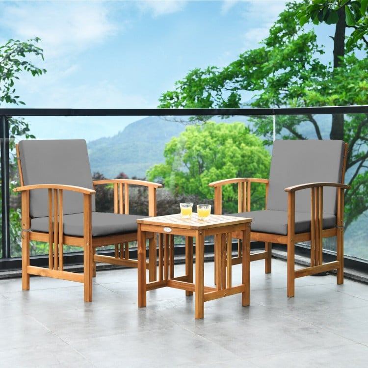 Two acacia wood chairs with gray cushions and a coffee table, perfect for outdoor patio relaxation.
