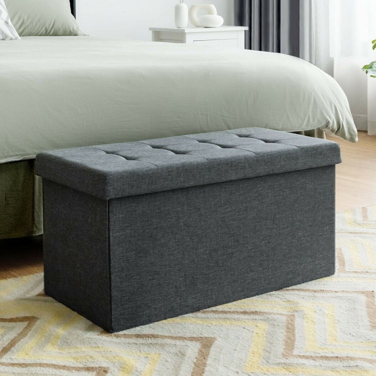 Foldable dark gray fabric storage ottoman with tufted top, spacious interior for blankets and clothes, ideal for.