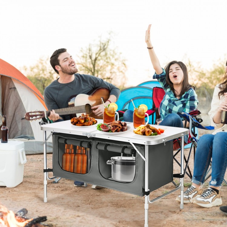 Height adjustable gray folding camping table with large storage area, perfect for outdoor picnics and barbecues.