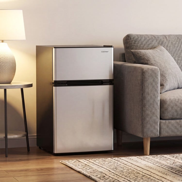 Silver 3.2 cu.ft mini fridge with double doors, featuring interior LED light and adjustable foot pads for stability.