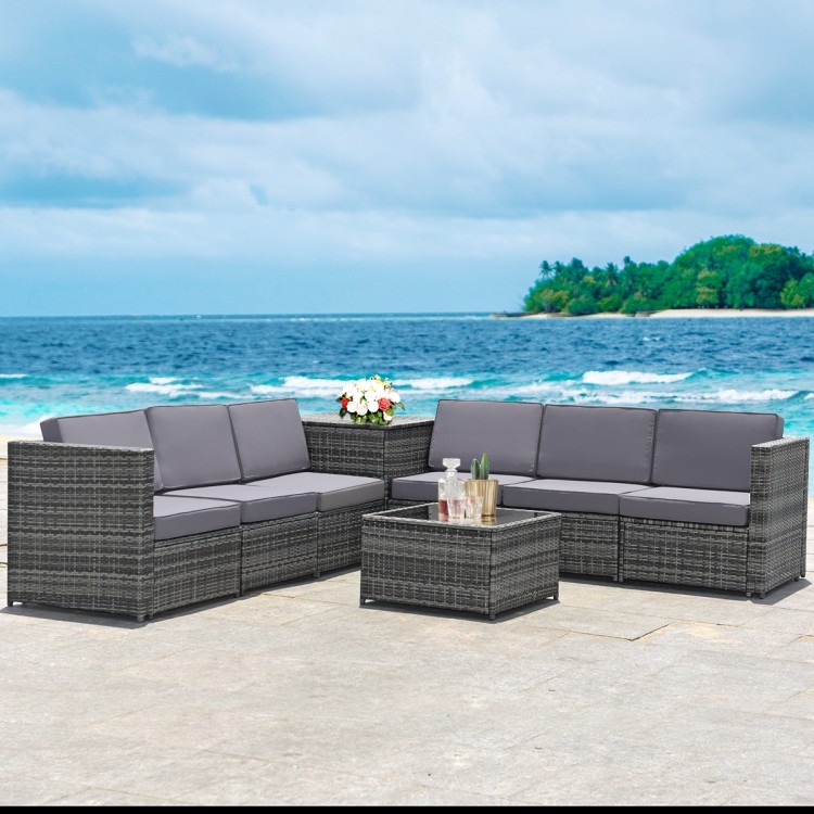 Gray 8-piece wicker sofa rattan dining set with storage table, ideal for outdoor relaxation by the sea.