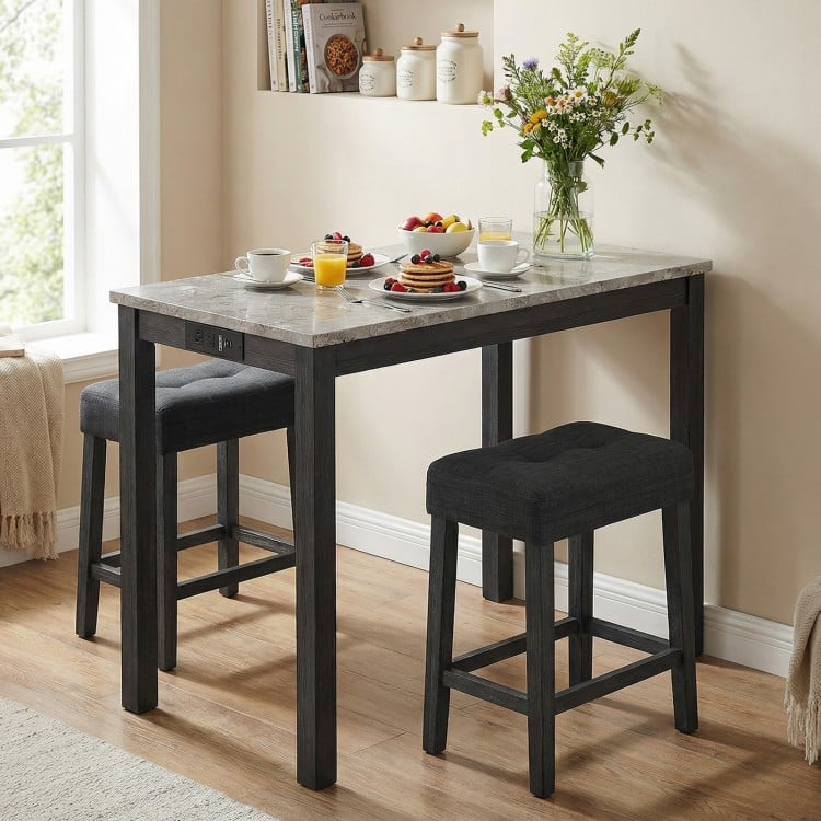 3-piece bar table set with faux marble top, gray upholstered stools, and side charging station for convenient use.