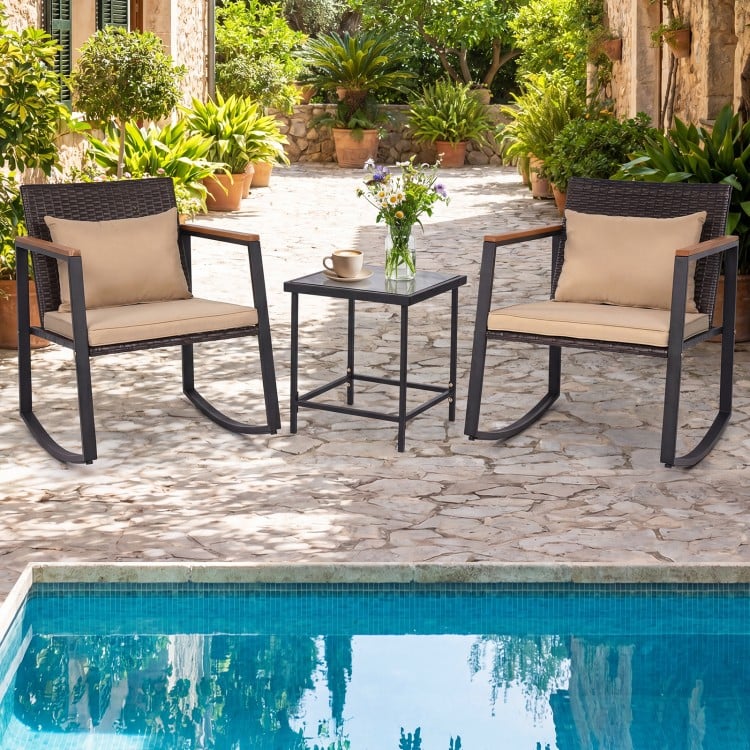 Outdoor rocking bistro set featuring wicker chairs with soft cushions and a tempered glass coffee table, perfect for.