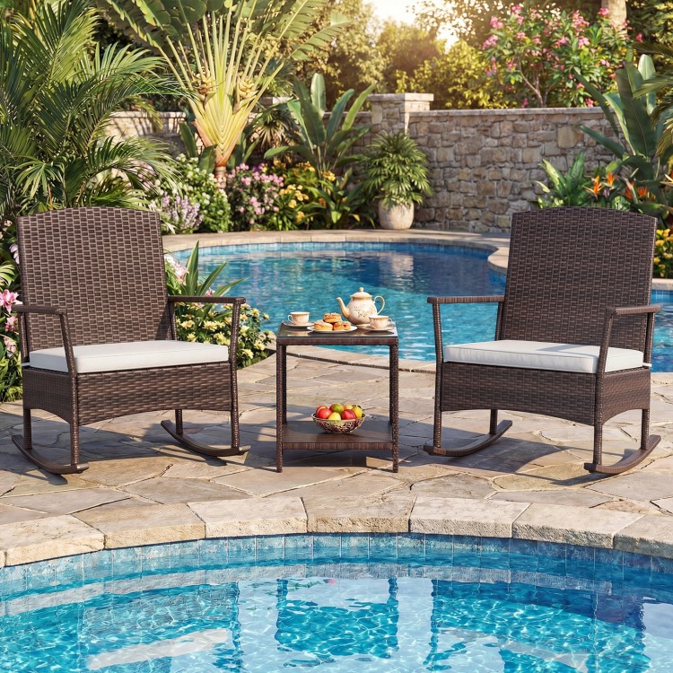 Two wicker rocking chairs with off-white cushions and a two-tier coffee table, perfect for relaxing by the poolside.