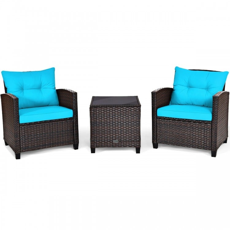 Two cushioned patio chairs with turquoise cushions and a coffee table, made of hand-woven rattan for outdoor use.