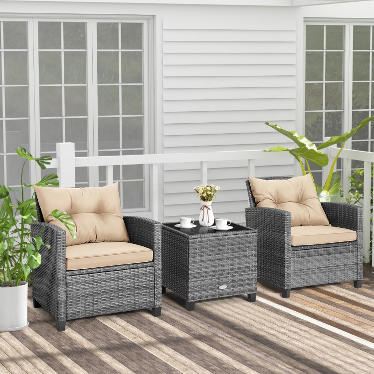 Two beige cushioned chairs with a compact glass-top table in a wicker conversation set for outdoor relaxation.