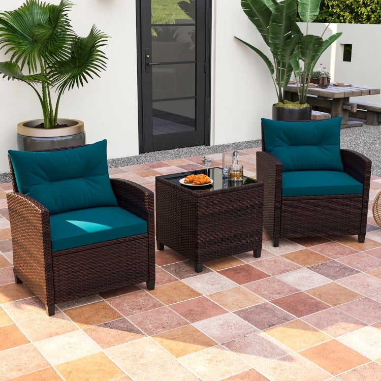 Two peacock blue cushioned rattan chairs and a coffee table, perfect for outdoor patio relaxation.