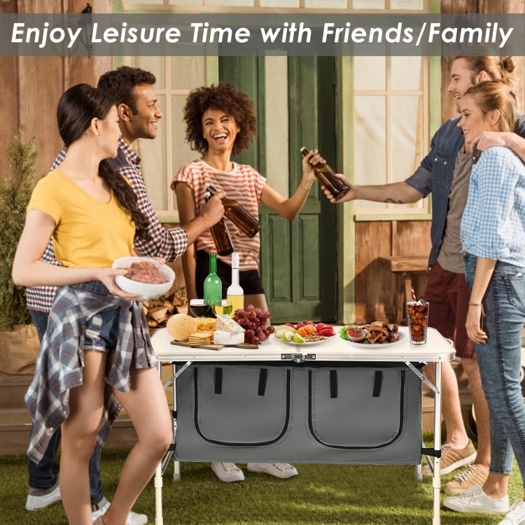 Height adjustable gray folding camping table with large storage area, perfect for picnics and outdoor gatherings.