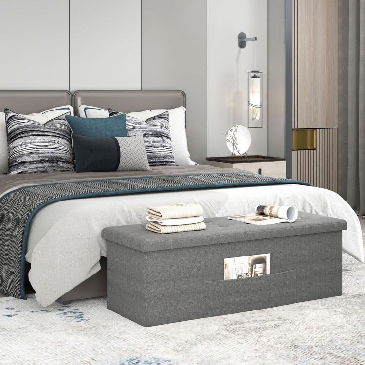 Folding storage ottoman bench in dark gray with padded seat, ideal for bedroom organization and extra seating.