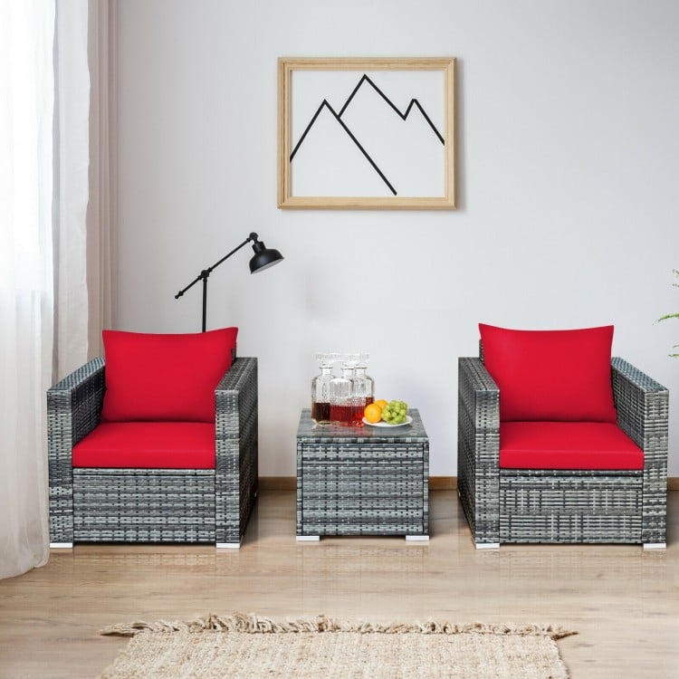 Two cushioned red chairs and a glass-top table from a 3-piece patio rattan furniture set for outdoor relaxation.