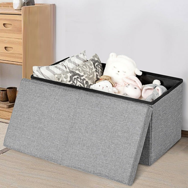 Light gray folding storage ottoman with lift top, featuring spacious interior for blankets and toys, perfect for home.