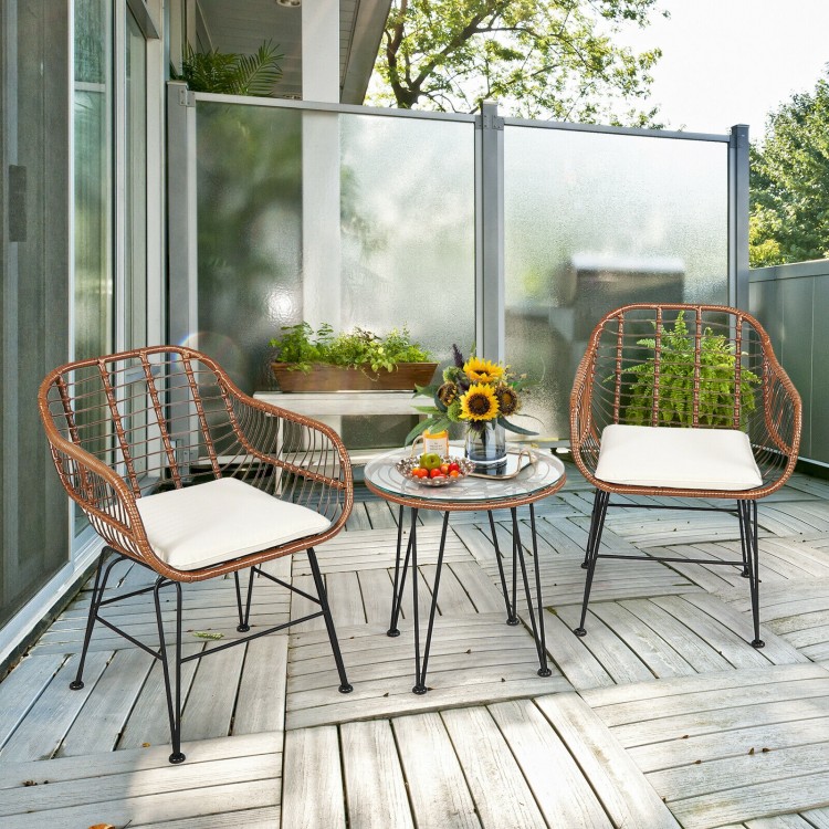 Two armchairs and a side table from a 3-piece patio rattan bistro set with white cushions, perfect for outdoor.