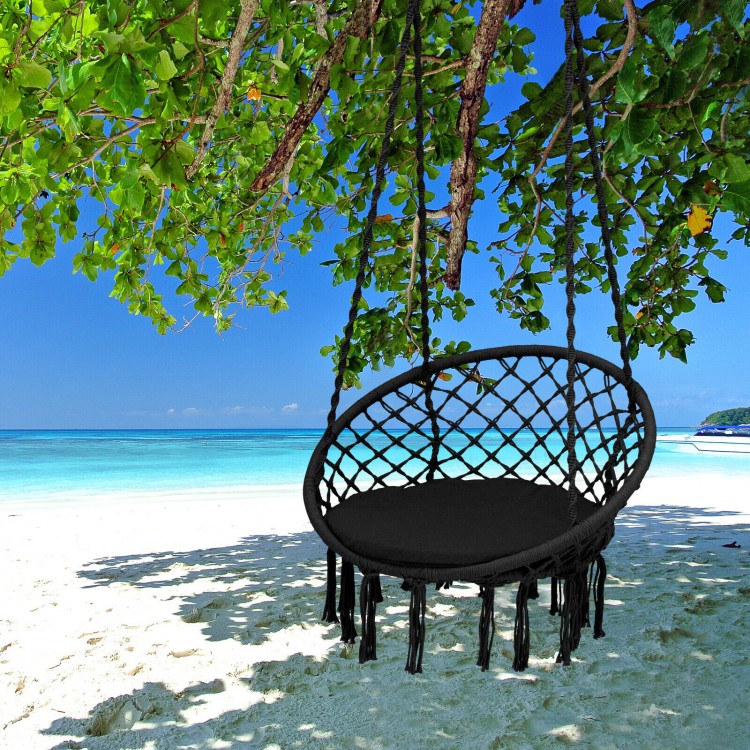 Cushioned black hammock swing chair hanging from a tree, perfect for outdoor relaxation by the beach.