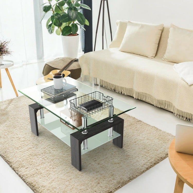Rectangular tempered glass coffee table with black legs and bottom shelf, ideal for modern living room decor.
