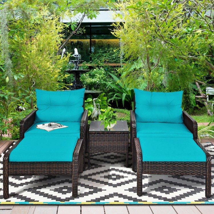 Two turquoise cushioned single sofas and a tea table in a brown rattan patio furniture set for outdoor relaxation.